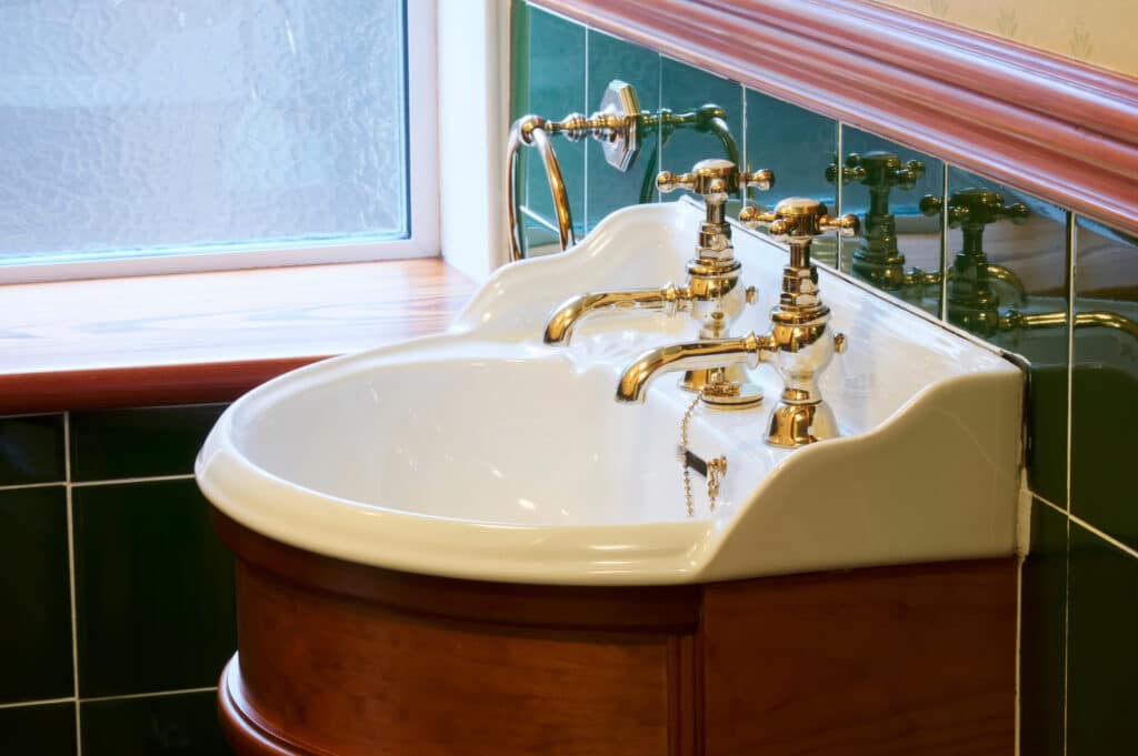 New luxury hotel vintage brass gold plated pillar taps in ensuite bathroom at wash basin UK