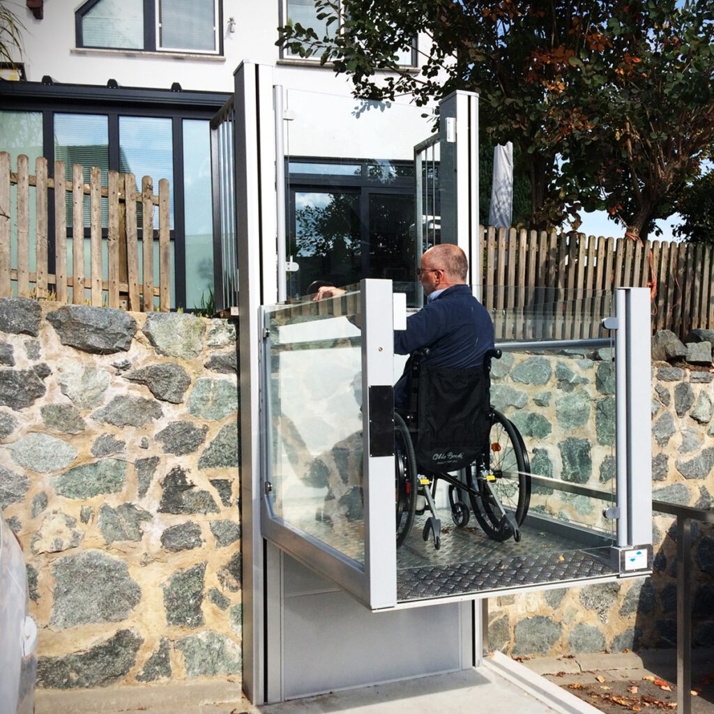 a step lift helping a disabled man in a wheelchair at his home