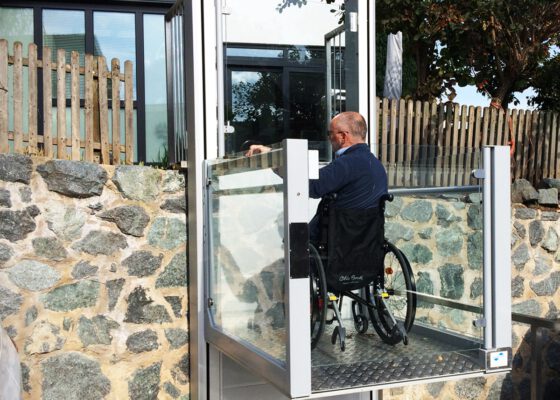 a step lift helping a disabled man in a wheelchair at his home