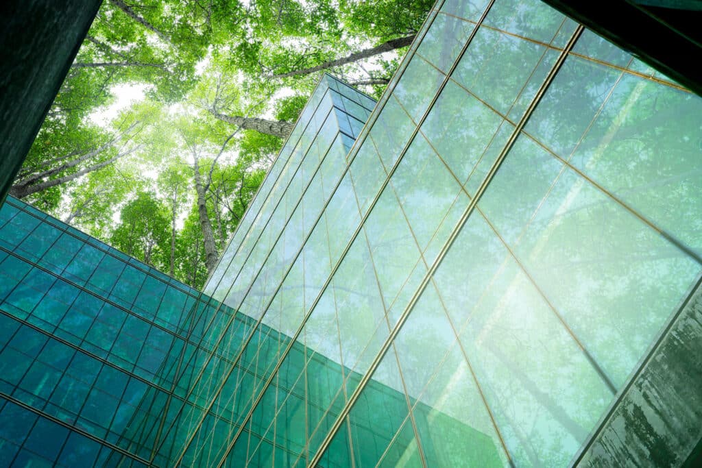 Eco-friendly building in modern city. Sustainable glass office building with trees for reducing CO2. Green architecture. Building with green environment. Sustainability corporate. Net zero emissions.