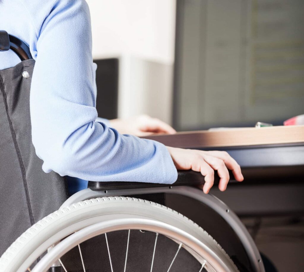 Invalid or disabled young business woman person sitting wheelchair working office desk computer