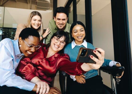 Group of diverse coworkers smiling while taking a selfie in their office space
