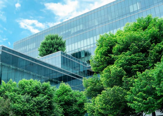 Eco-friendly building in the modern city. Sustainable glass office building with trees for reducing heat and carbon dioxide. Office building with green environment. Corporate building reduce CO2.